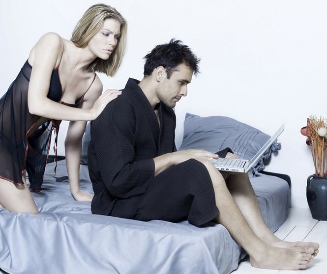 beautiful young caucasian couple in a bed on isolated background with computer laptop