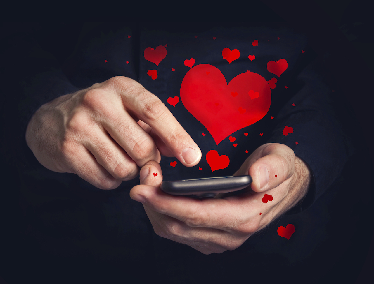 Man typing love text messages on a smartphone for Valentine's