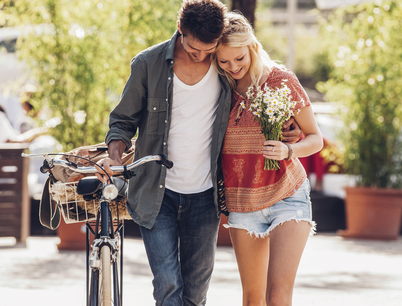 Young couple in love with bicycle and bunch of flowers
